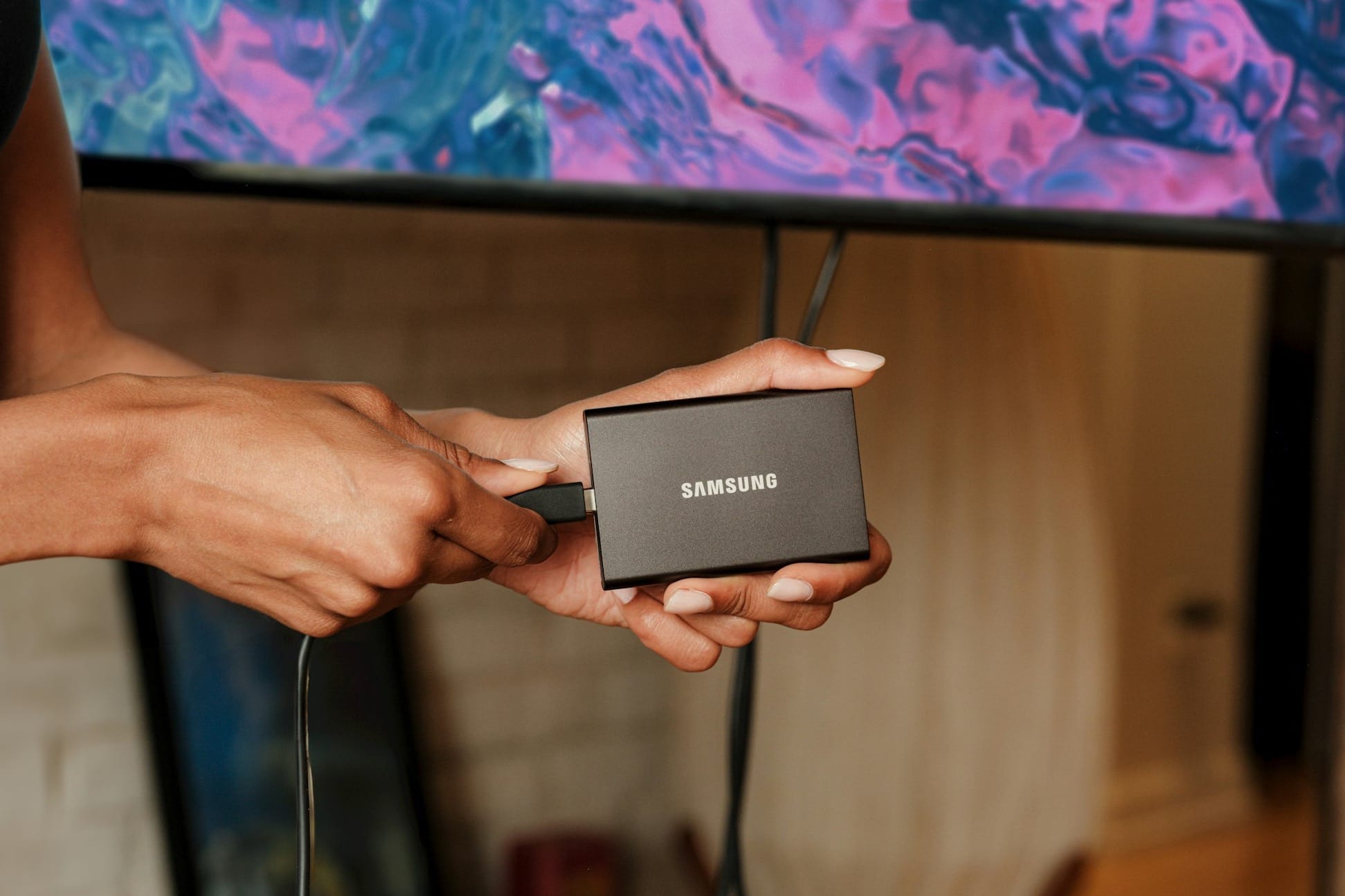 A person holding a device in front of a TV